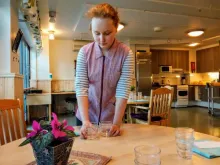 TET- harjoittelija laittaa astioita pöytään