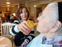 Palvelupäällikkö auttaa vanhusta syömisessä