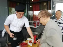 kesäkoululainen antaa makkaraa asiakkaalle